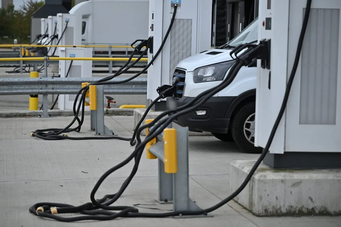Row of high-power chargers at a distribution centre loading dock, with an electric van charging
