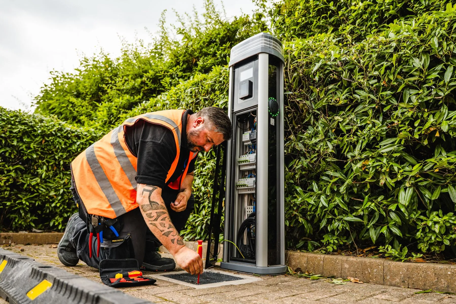 An engineer in a hi-vis vest working on an open electric vehicle charge point
